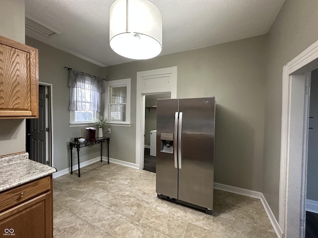 kitchen featuring stainless steel fridge with ice dispenser and a textured ceiling