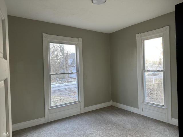 empty room with light colored carpet and a healthy amount of sunlight