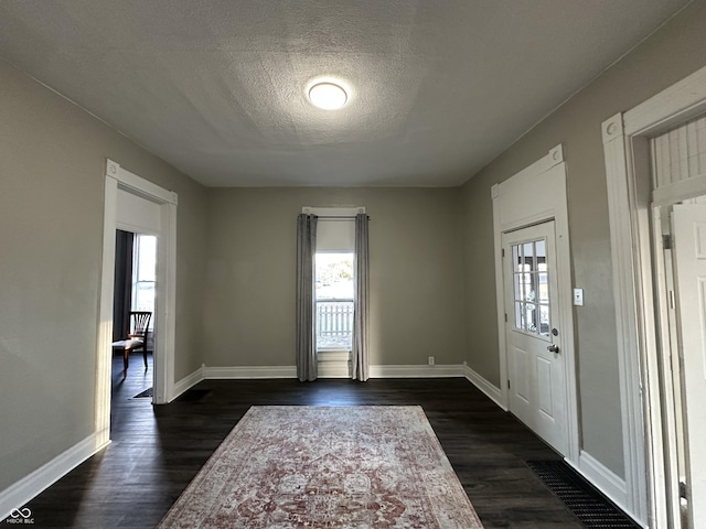 foyer entrance with a textured ceiling and dark hardwood / wood-style flooring