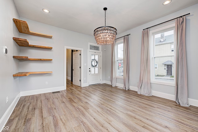 foyer entrance with light hardwood / wood-style floors and an inviting chandelier