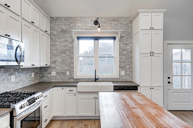 kitchen with appliances with stainless steel finishes, light wood-type flooring, white cabinetry, and sink