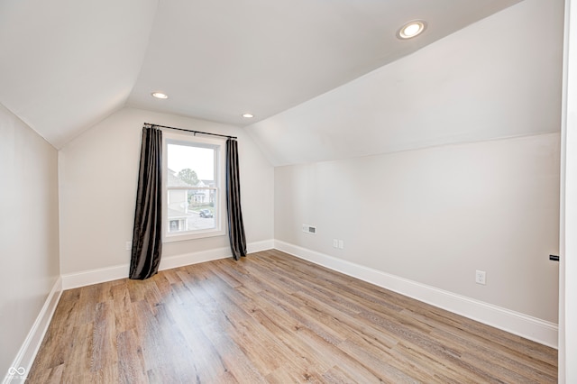 additional living space featuring vaulted ceiling and light wood-type flooring