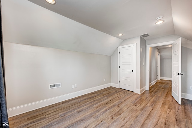 additional living space featuring vaulted ceiling and hardwood / wood-style flooring