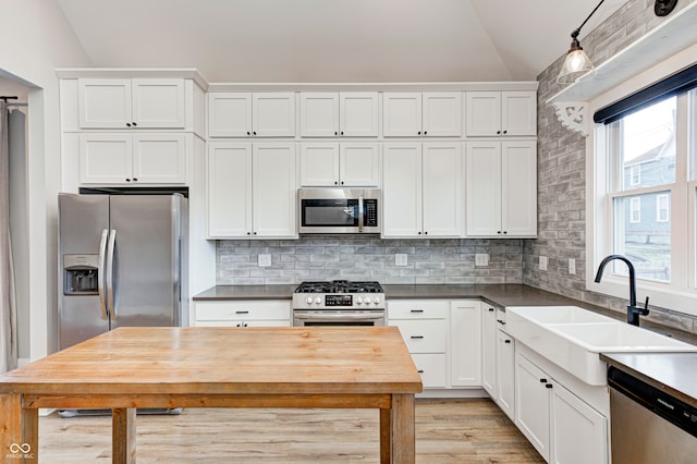 kitchen featuring white cabinets, appliances with stainless steel finishes, and lofted ceiling