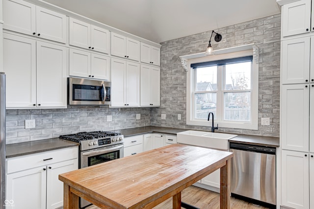 kitchen featuring white cabinets, stainless steel appliances, tasteful backsplash, and sink