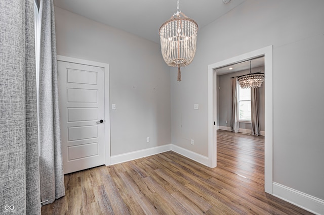 unfurnished room with hardwood / wood-style floors and a notable chandelier