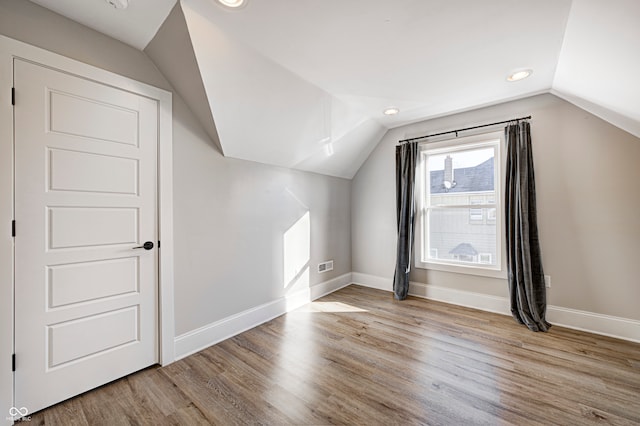 additional living space with light hardwood / wood-style flooring and lofted ceiling