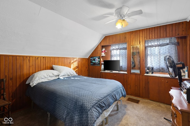 bedroom featuring ceiling fan, wooden walls, lofted ceiling, and carpet