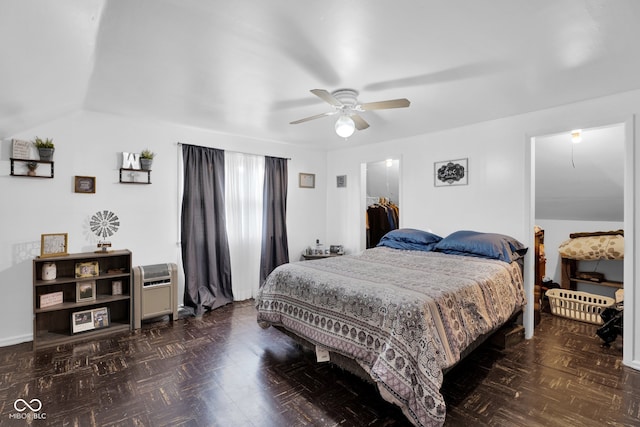 bedroom with a closet, a spacious closet, dark parquet floors, lofted ceiling, and ceiling fan