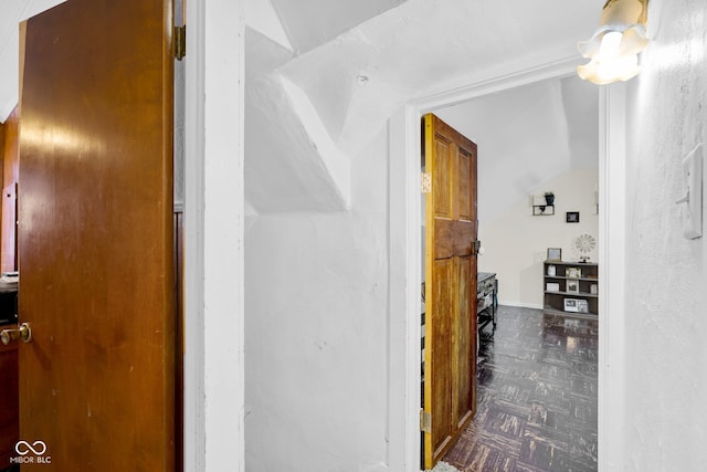 hall with dark parquet flooring and vaulted ceiling