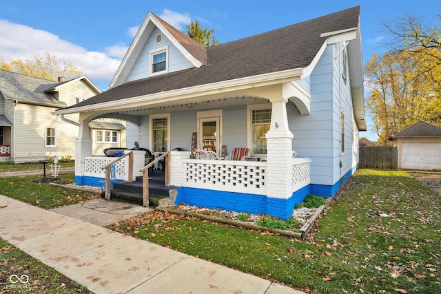 bungalow-style house with an outbuilding, a garage, covered porch, and a front yard