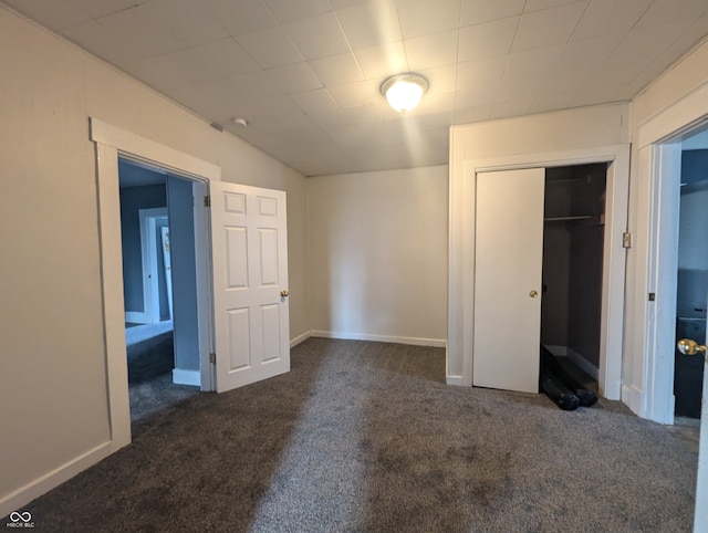 unfurnished bedroom featuring dark colored carpet and a closet