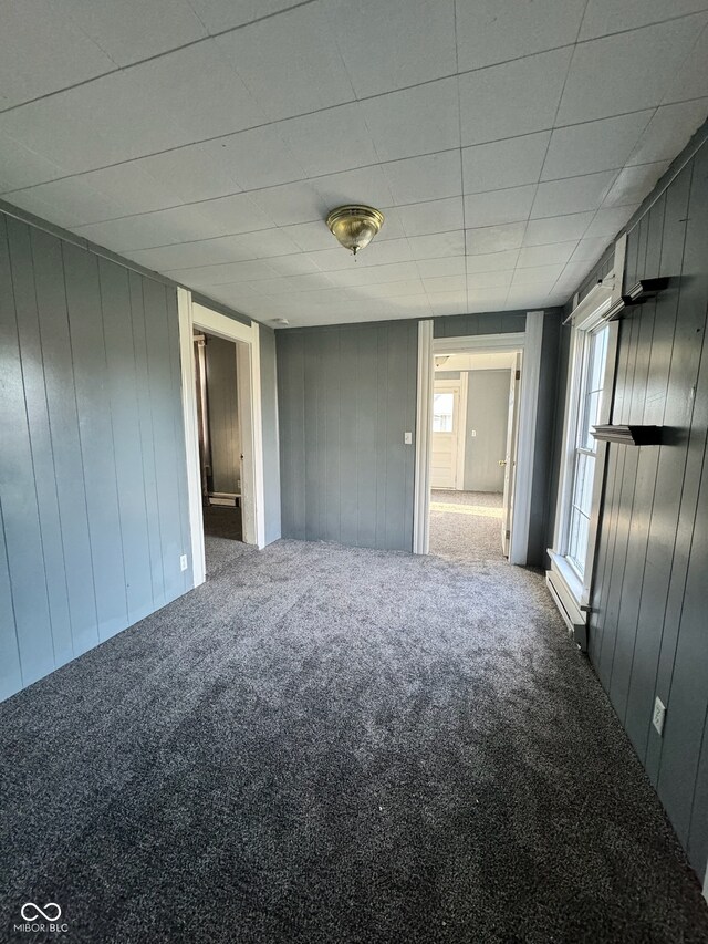 unfurnished bedroom with carpet and wooden walls