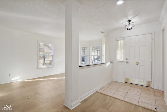 foyer entrance featuring light hardwood / wood-style floors, a textured ceiling, and crown molding