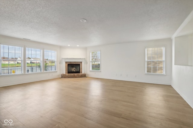 unfurnished living room featuring a textured ceiling, light hardwood / wood-style floors, and a fireplace