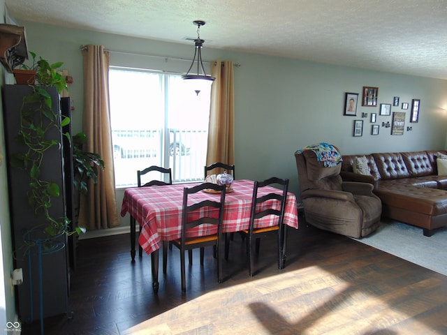 dining space with dark wood-type flooring and a textured ceiling