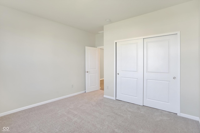 unfurnished bedroom with light colored carpet and a closet