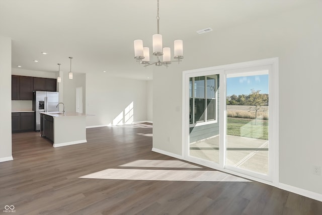 unfurnished dining area featuring dark wood-type flooring, a chandelier, and sink