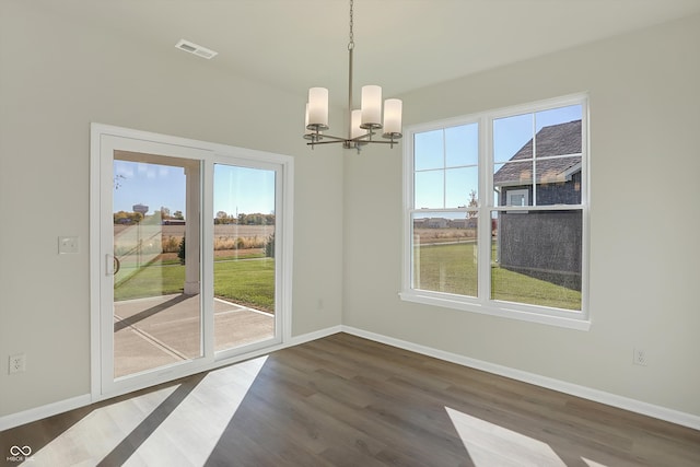 unfurnished dining area with dark wood-type flooring and a notable chandelier