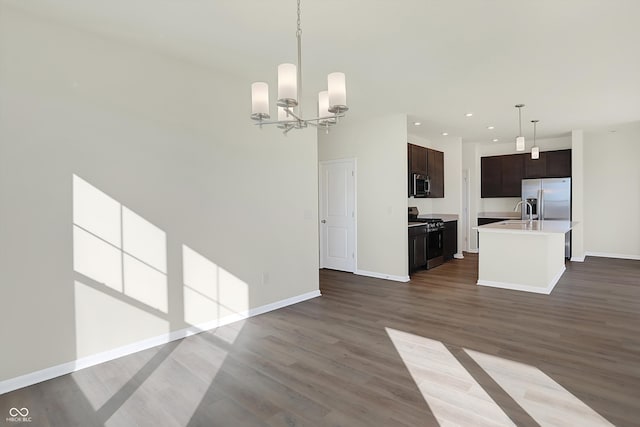 kitchen with stainless steel appliances, dark brown cabinetry, wood-type flooring, a chandelier, and pendant lighting