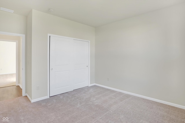 unfurnished bedroom with light colored carpet and a closet