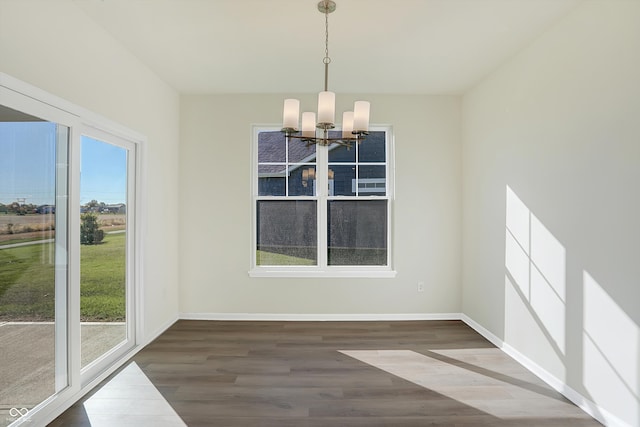 unfurnished dining area with wood-type flooring and an inviting chandelier