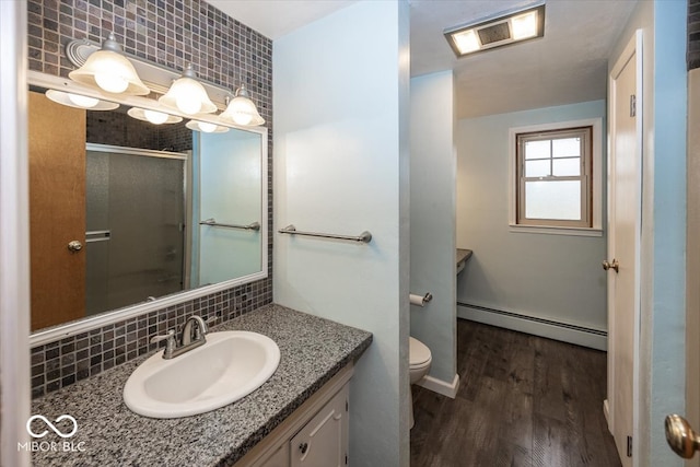 bathroom featuring a baseboard heating unit, hardwood / wood-style flooring, toilet, and backsplash