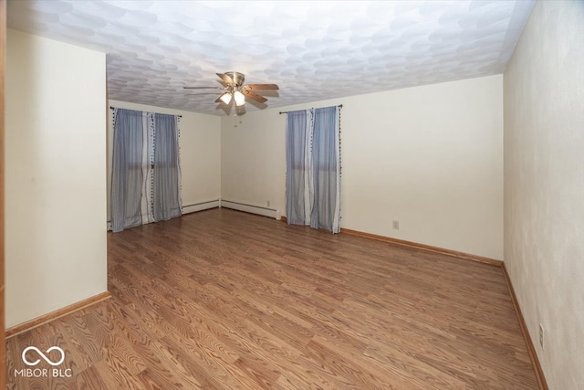 empty room with ceiling fan, light wood-type flooring, and baseboard heating