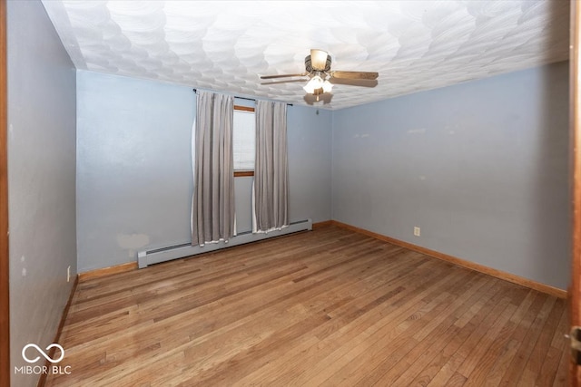 empty room with ceiling fan, light wood-type flooring, and a baseboard heating unit