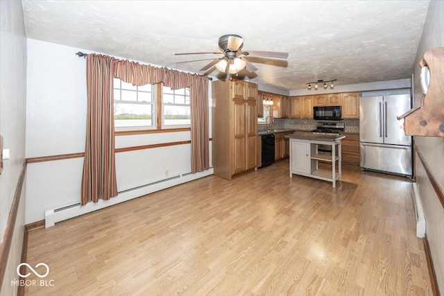 kitchen with light hardwood / wood-style floors, black appliances, ceiling fan, a kitchen island, and a baseboard radiator