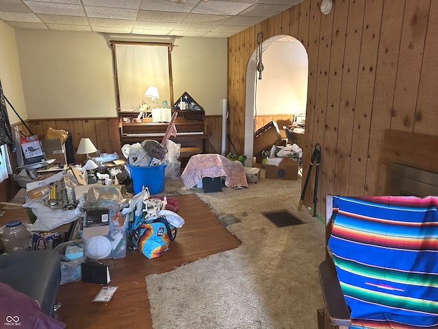 miscellaneous room with wooden walls, a drop ceiling, and carpet flooring