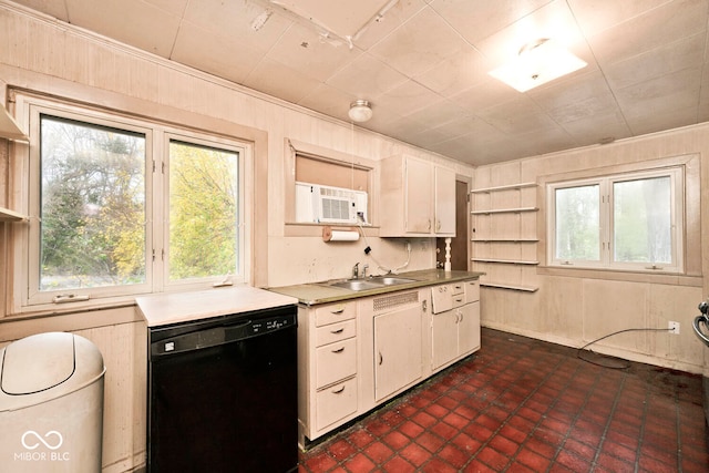 kitchen with black dishwasher, white cabinetry, sink, and wood walls