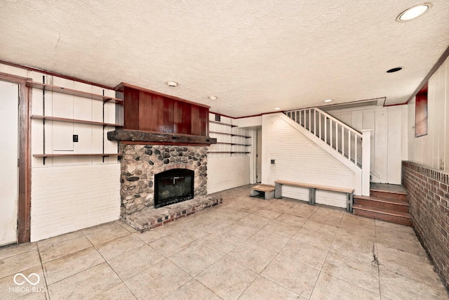 unfurnished living room featuring a stone fireplace, a textured ceiling, crown molding, and light tile patterned flooring