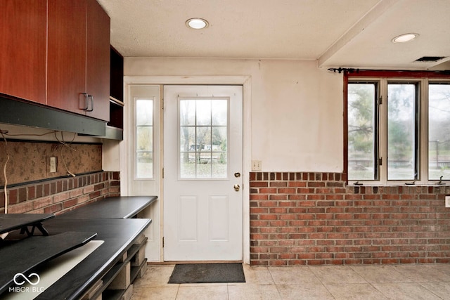 interior space featuring plenty of natural light, light tile patterned floors, and brick wall