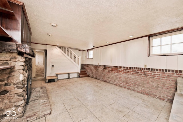 interior space with wooden walls, a textured ceiling, and light tile patterned floors