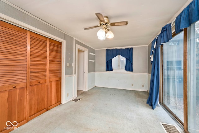 carpeted empty room with ceiling fan and ornamental molding