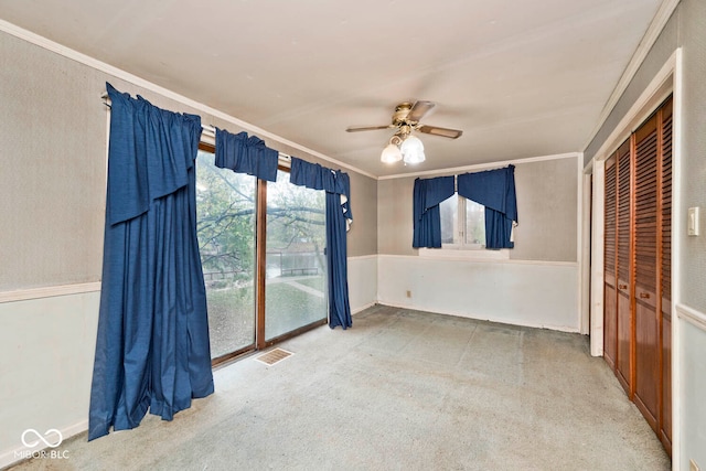 unfurnished room with carpet floors, ceiling fan, and crown molding