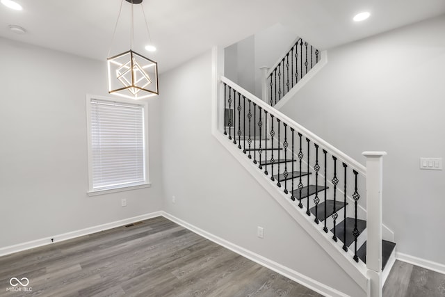 stairs with hardwood / wood-style flooring and a chandelier