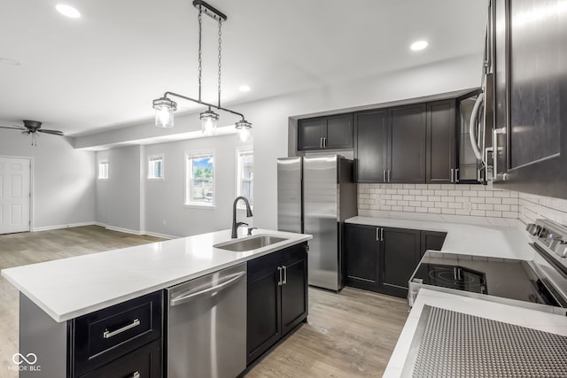 kitchen featuring light hardwood / wood-style floors, sink, appliances with stainless steel finishes, a kitchen island, and decorative backsplash