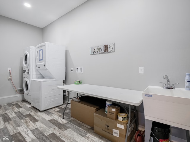 washroom with stacked washing maching and dryer, wood-type flooring, and sink