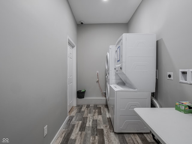 clothes washing area with stacked washing maching and dryer and dark hardwood / wood-style flooring