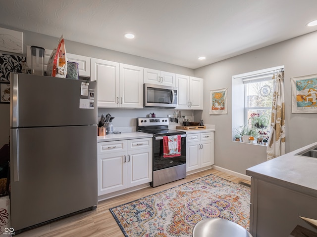 kitchen with white cabinetry, light wood-type flooring, and stainless steel appliances