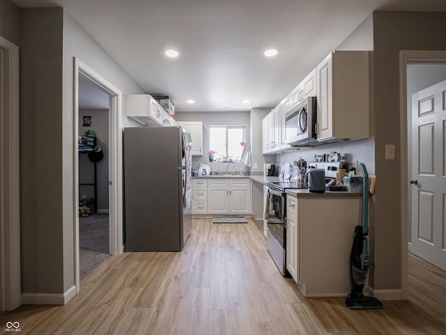 kitchen featuring white cabinets, light wood-type flooring, appliances with stainless steel finishes, and sink