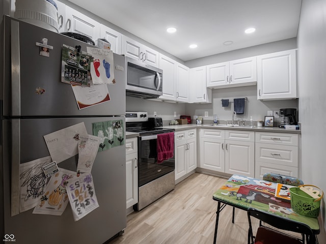 kitchen with stainless steel appliances, light hardwood / wood-style floors, white cabinetry, and sink