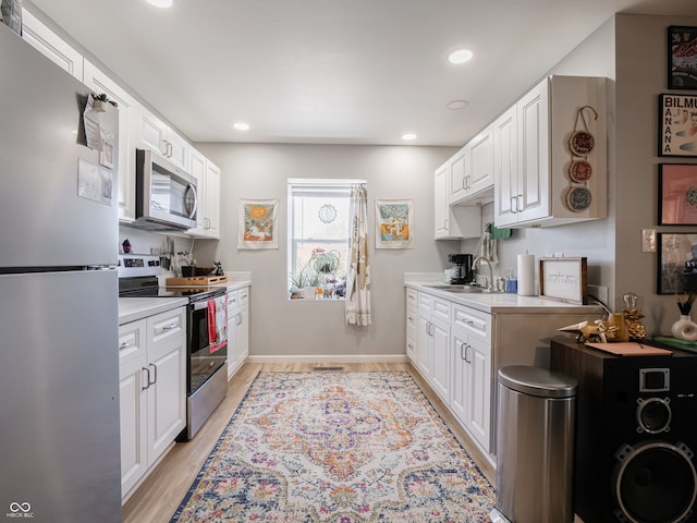 kitchen featuring white cabinets, light wood-type flooring, appliances with stainless steel finishes, and sink