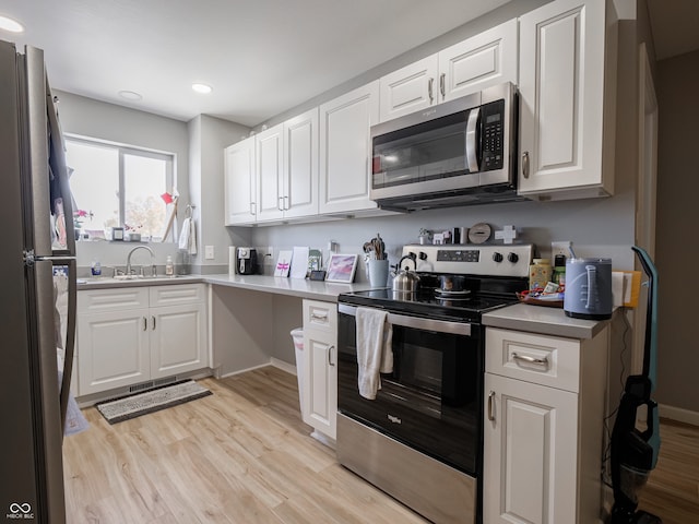 kitchen with white cabinets, light wood-type flooring, and stainless steel appliances