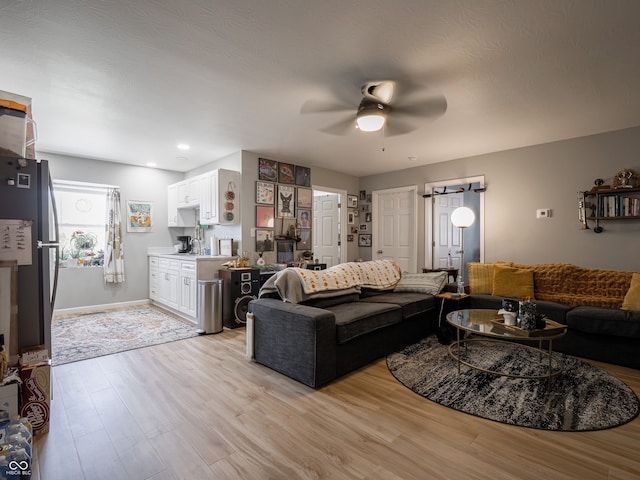 living room with light hardwood / wood-style floors, a barn door, and ceiling fan