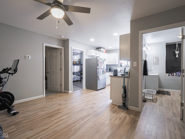 interior space featuring ceiling fan, light hardwood / wood-style floors, stainless steel fridge, and white cabinetry