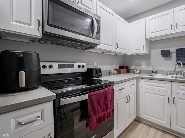 kitchen featuring white cabinetry, light hardwood / wood-style floors, stainless steel appliances, and sink