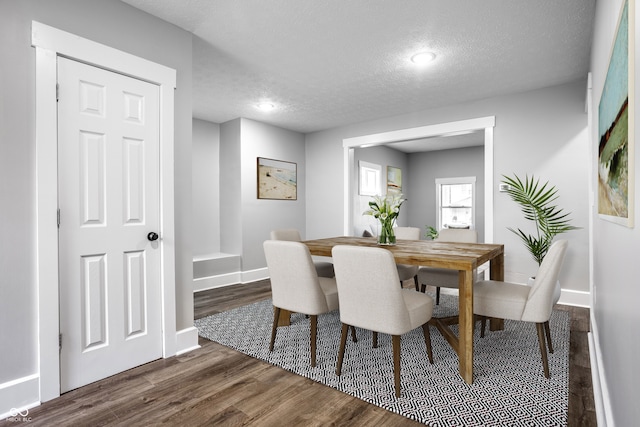 dining area featuring dark wood-type flooring and a textured ceiling